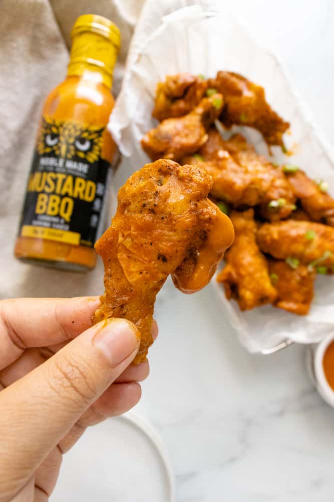 mustard bbq chicken wings, one piece is being held up for a close up