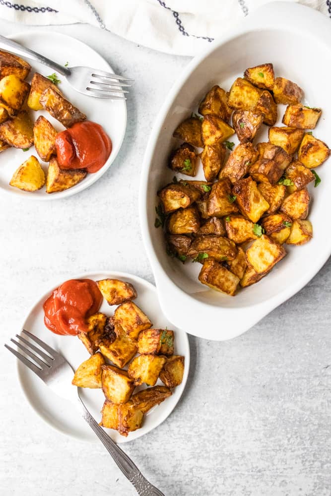 air fryer home fries in a large dish and small plates with ketchup