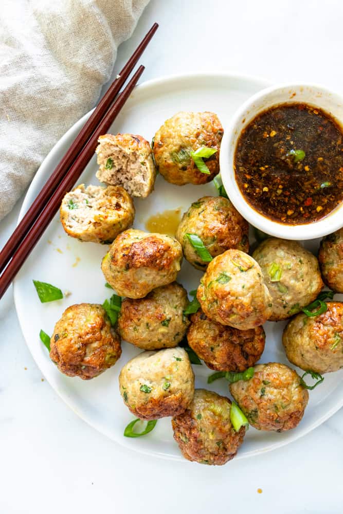 a plate with pork dumpling meatballs, one is cut in half to show how juicy and moist it is