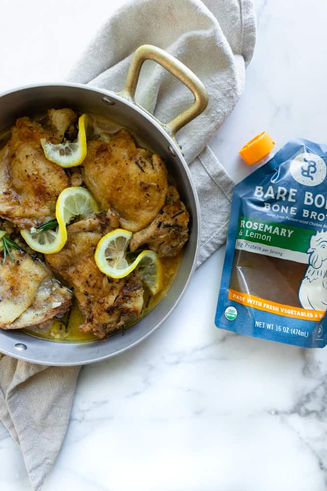 Instant Pot Creamy Rosemary Lemon Chicken in a pot next to a bag of Bare Bones Rosemary Lemon Chicken Bone Broth