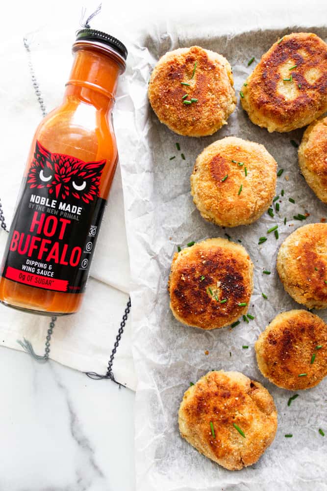 spicy chicken croquettes next to a bottle of the new primal hot buffalo sauce