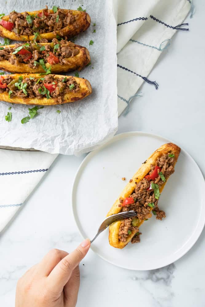 a stuffed plantain on a plate that's being cut