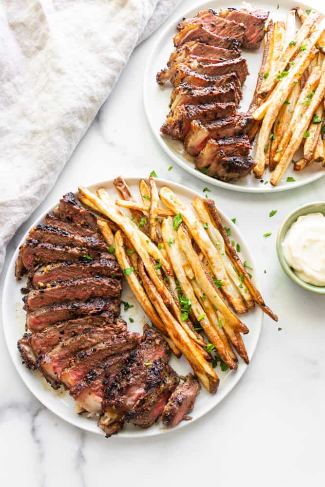 two plates of steak frites with garlic mayo dip