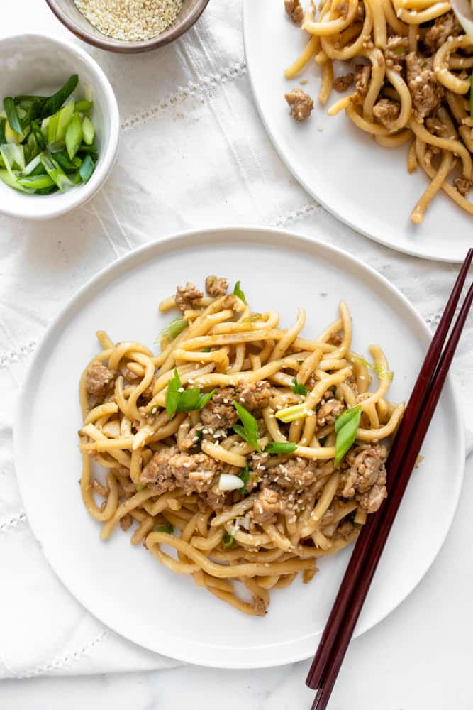 sesame ginger udon stir fry on a plate with chopsticks