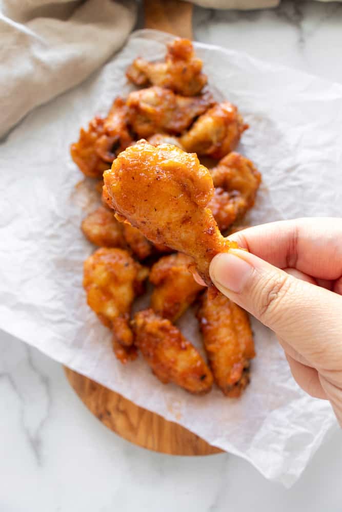 holding a drumstick of the Spicy Honey Butter Chicken Wings