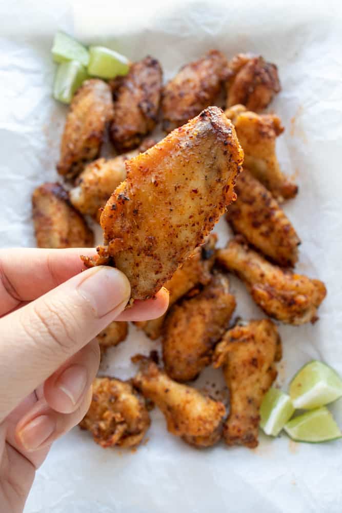 a hand holding up one of the szechuan pepper chicken wings