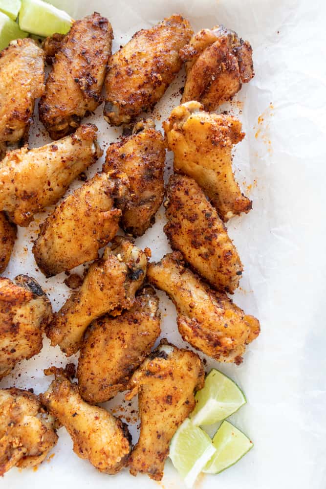 szechuan pepper chicken wings on a platter with lime wedges