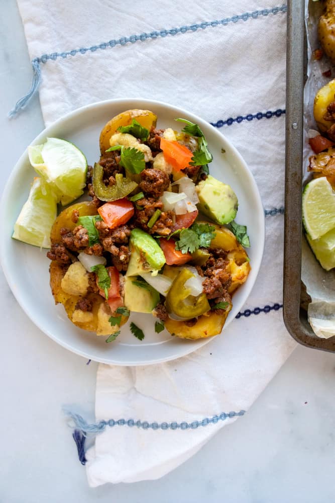 crispy smashed potato nachos on a small plate next to the tray