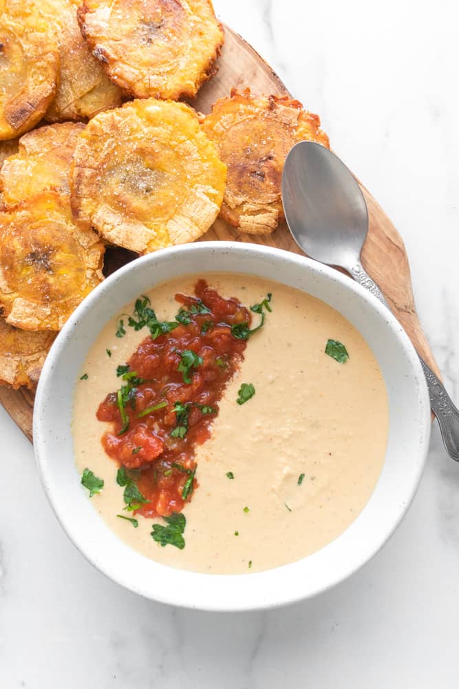 salsa con queso in a bowl next to tostones