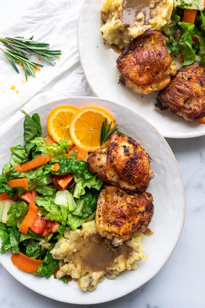 orange rosemary chicken plated with a fresh salad and mashed potatoes with gravy