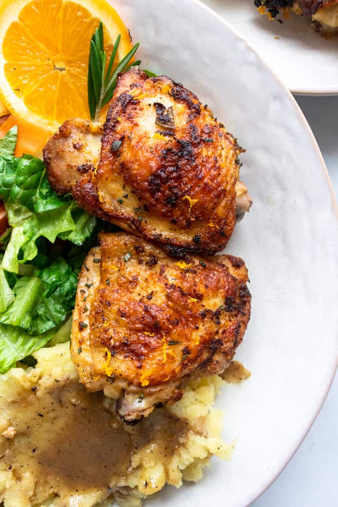 close up of the orange rosemary chicken plated with a salad and mashed potatoes with gravy