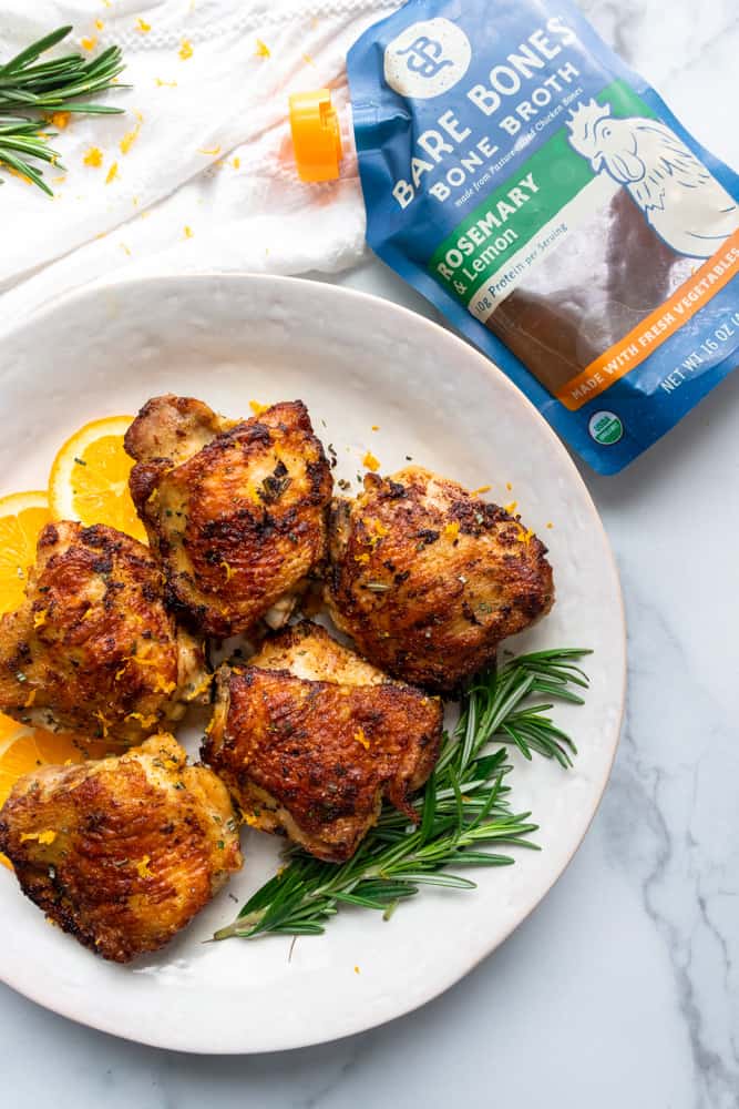 orange rosemary chicken on a plate next to bare bones broth package