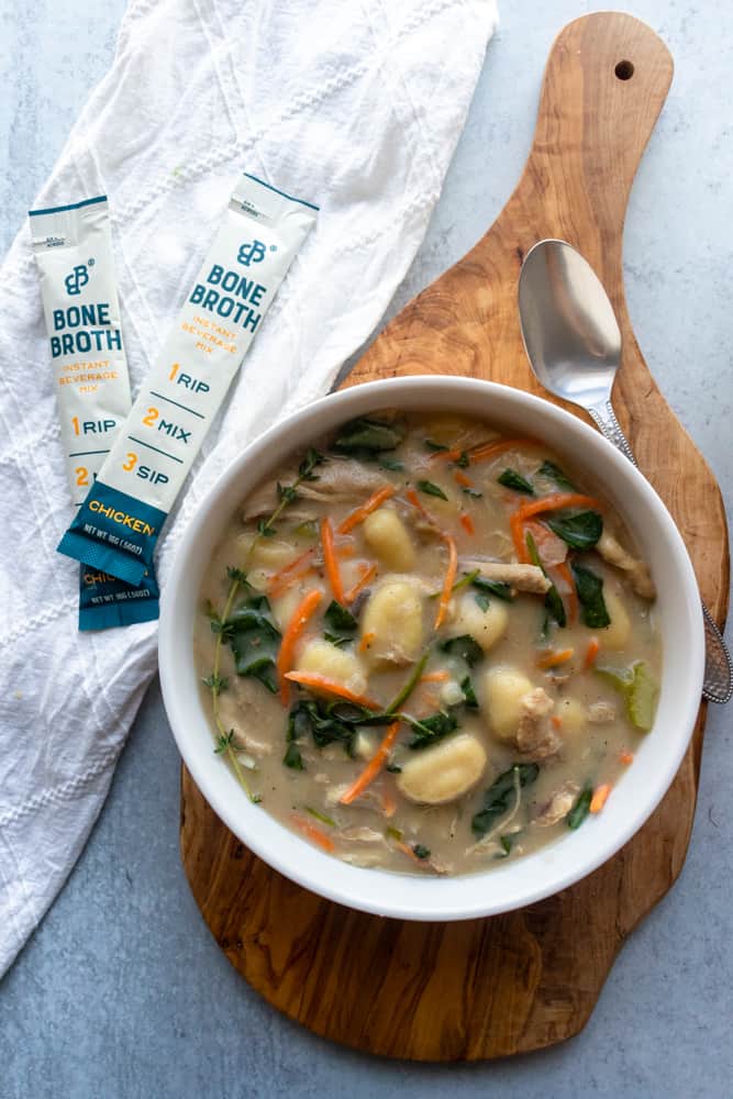 a bowl of chicken gnocchi soup next to two packets of instant beverage mix