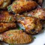 lao grilled chicken (pieng gai) on a plate garnished with cilantro