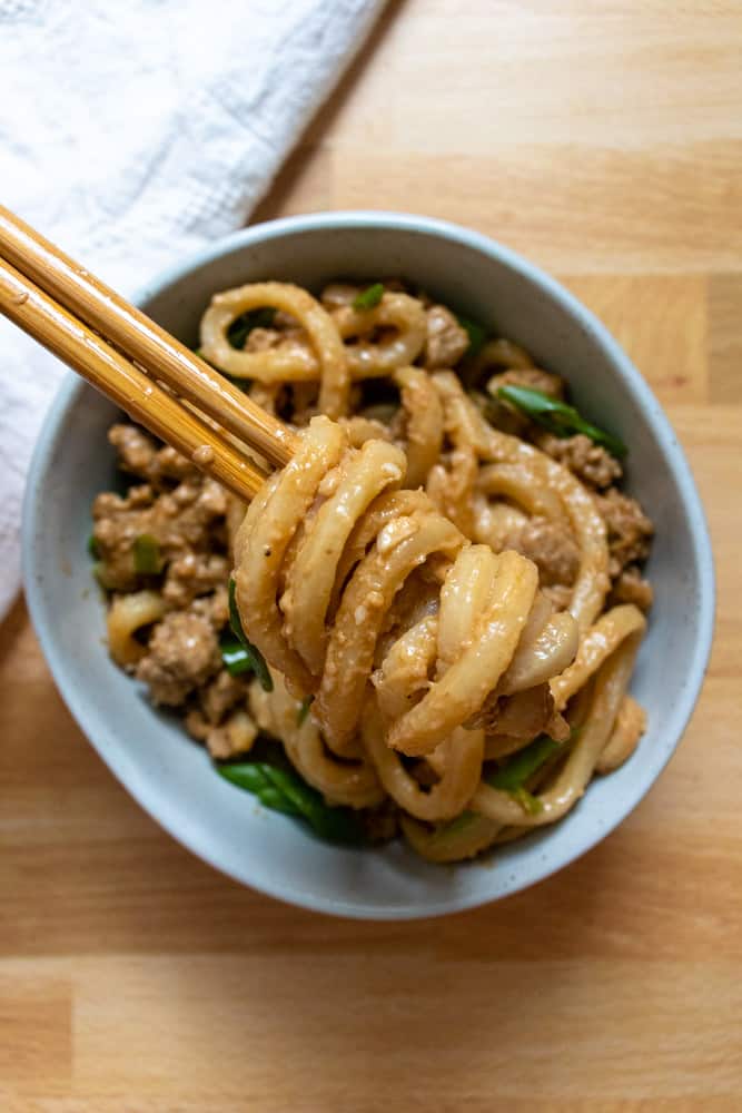 peanut garlic udon stir fry being picked up by chopsticks