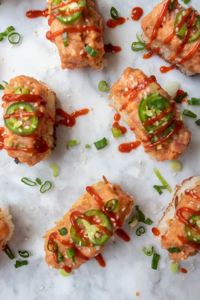 Spicy Tuna Crispy Rice with jalapeno slices and sriracha sauce on top