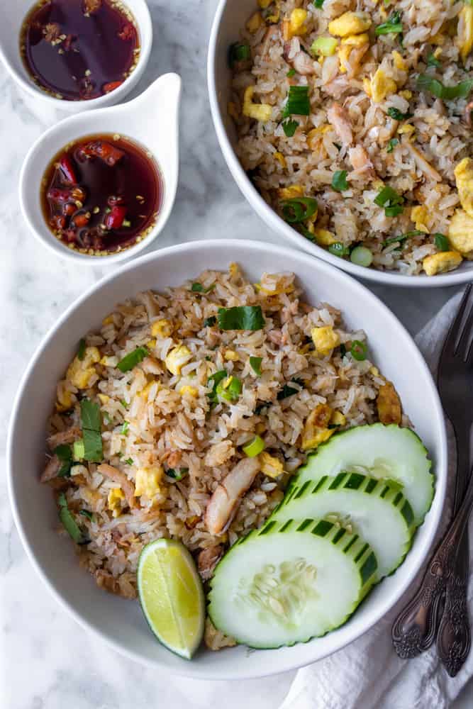 Two bowls of Thai Crab Fried Rice with cucumber slices and nam prik pla