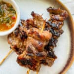 moo ping (thai grilled pork) on a plate with jeow som