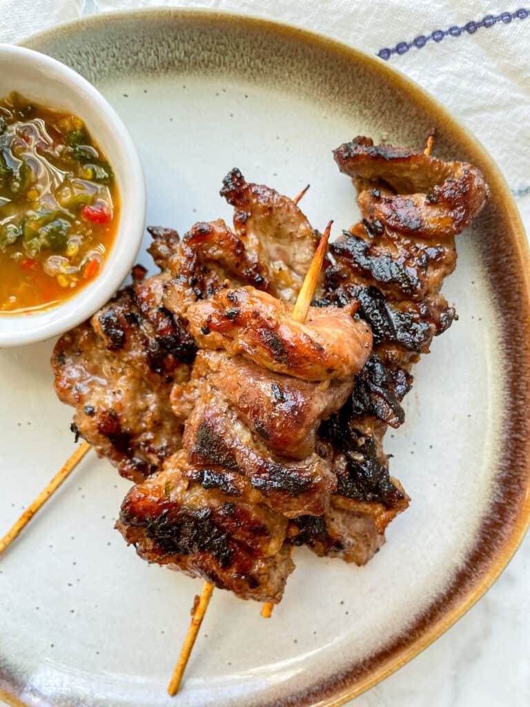 moo ping (thai grilled pork) on a plate with jeow som